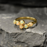 Ethiopian Opal Bypass Ring in gold with six cabochon stones aligned in a curved wrap setting, a stylish jewelry design that radiates flashes of fire colors and adds a modern edge, making it a thoughtful October birthstone gift idea. Perfect to wear at weddings, cocktail parties, and romantic dinners for a bold yet refined look.