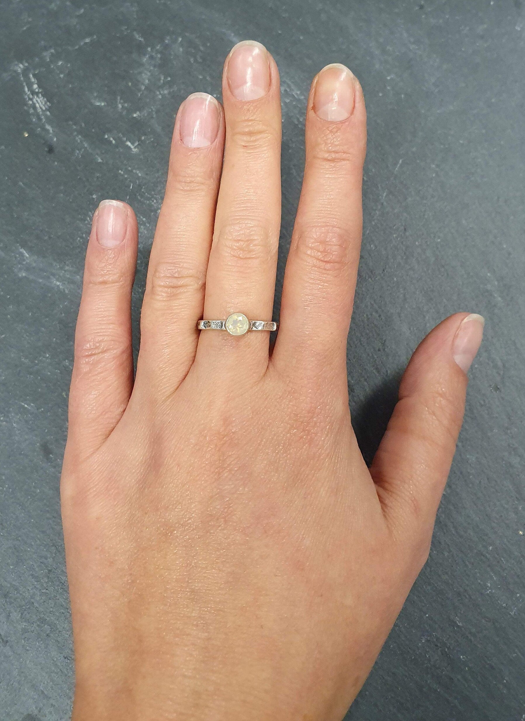 Ethiopian Opal Hammered Solitaire Ring styled with a black scoop blouse and high-rise jeans, worn on the index finger with bare nails; flashes of fire colors add subtle shimmer while the bezel offers everyday durability; ideal for date nights, concerts, and rooftop dinners.Worn for office days, brunch dates, music festivals, casual weekends, and small weddings.