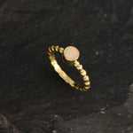 Ethiopian Opal Bezel Promise Ring in gold featuring a round diamond cut stone set in a bubble tennis band design, a stylish jewelry piece radiating flashes of fire colors while symbolizing love and commitment, making it a meaningful October birthstone gift idea. Perfect for engagements, anniversaries, and elegant evening occasions to showcase understated brilliance.