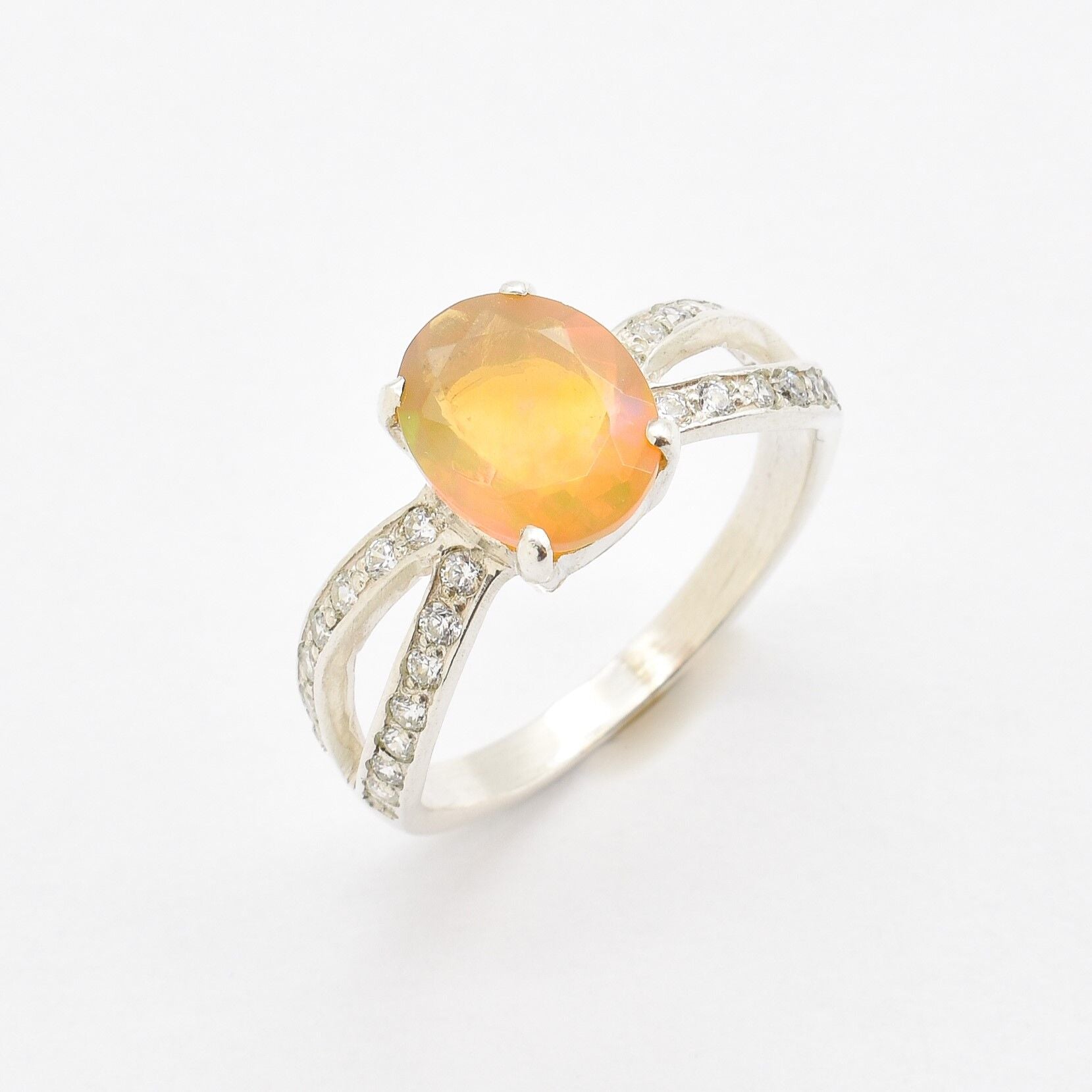 Ethiopian Opal Oval Ring in sterling silver with a 4 prong setting and split shank design. Jewelry style features a CZ pave band that adds brilliance around the opal gemstone, glowing with flashes of fire colors. Opal is known for inspiring creativity, passion, and emotional balance. A meaningful October birthstone gift for birthdays, anniversaries, and special milestones. Perfect to wear at weddings, evening dinners, formal events, and cocktail parties.