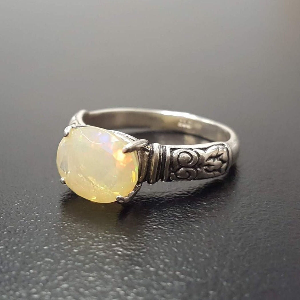 Ethiopian Fire Opal Sterling Silver Ring featuring a horizontal oval cut with a secure 4-prong setting. The engraved ornament band adds vintage charm, while the opal displays brilliant flashes of fire colors. A timeless October birthstone ring, perfect for birthdays, anniversaries, weddings, and milestone celebrations.