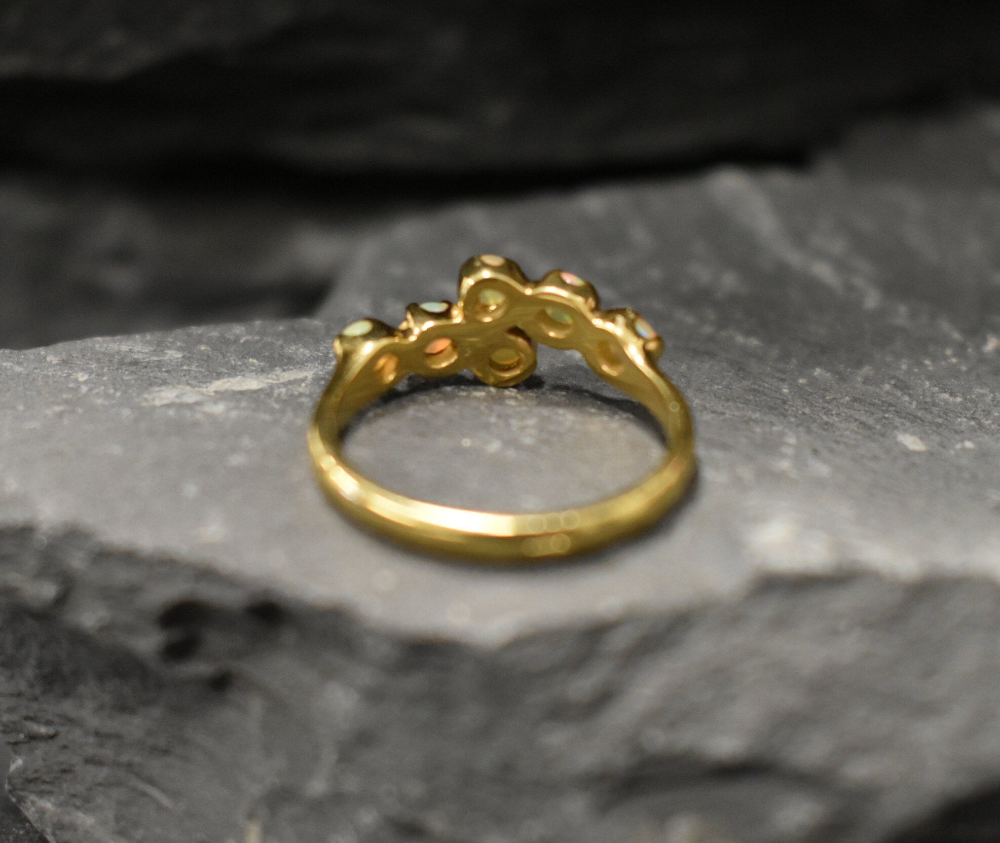 Ethiopian Opal Bypass Ring in gold with six cabochon stones aligned in a curved wrap setting, a stylish jewelry design that radiates flashes of fire colors and adds a modern edge, making it a thoughtful October birthstone gift idea. Perfect to wear at weddings, cocktail parties, and romantic dinners for a bold yet refined look.