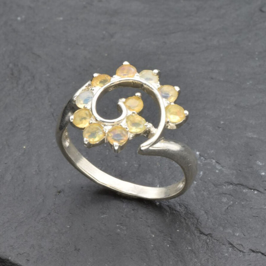 Opal Spiral Ring in sterling silver designed as a sunburst swirl statement jewelry piece offering radiant flashes of fire colors and boho charm, believed to inspire creativity and positivity, making it a thoughtful October birthstone gift idea. Perfect to wear at weddings, parties, and special occasions for a vibrant standout look.