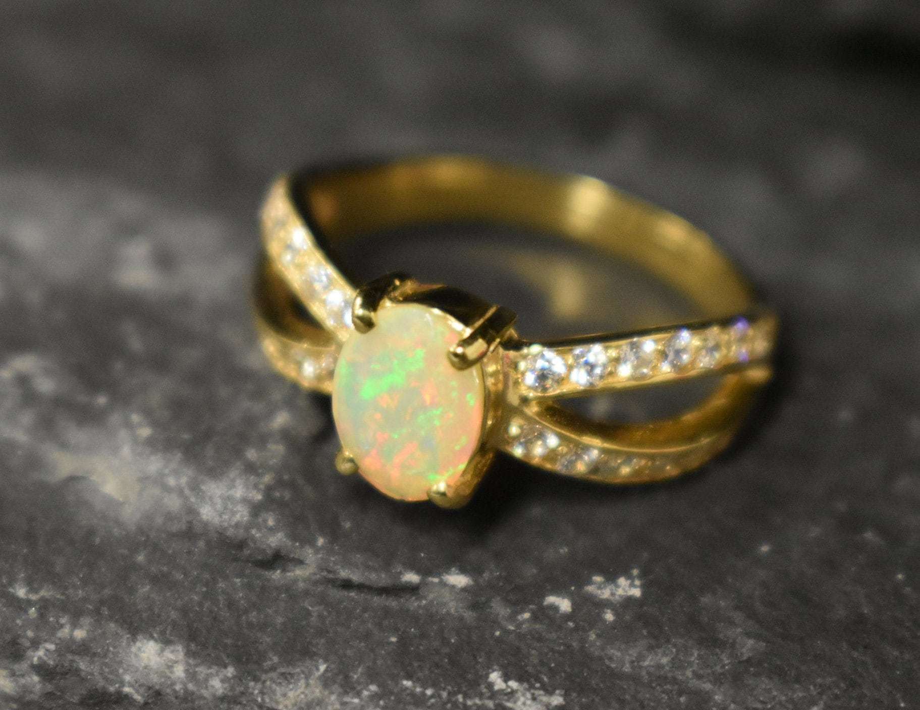 Opal Ring with split shank band and CZ pave setting showing flashes of fire colors, designed as elegant fine jewelry. Known for its emotional healing and creativity benefits, Opal is also the October birthstone and a thoughtful gift for birthdays or anniversaries. Perfect to wear at weddings, romantic dinners, and special evening celebrations.