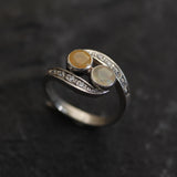 Two-Stone Opal Bypass Wave Ring in sterling silver showcasing cabochon-cut opals with flashes of fire colors and CZ pave accents for an elegant jewelry style. Known for enhancing emotional clarity and balance, this October birthstone ring makes a thoughtful and meaningful gift idea. Perfect for anniversaries, weddings, cocktail events, and celebratory occasions where sophistication shines.