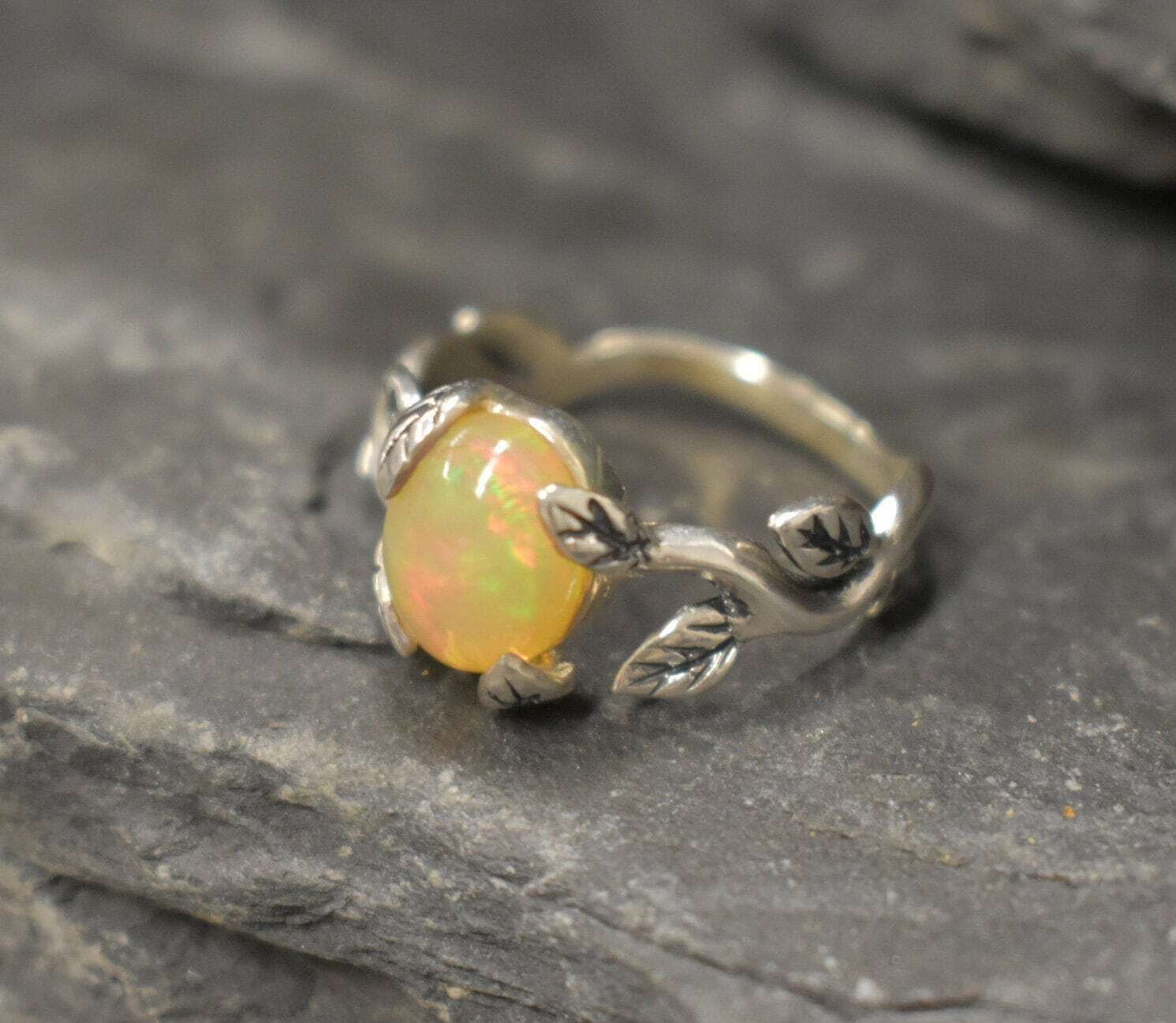 Opal Vine Ring in sterling silver with a cabochon cut gemstone framed by leaf and branch accents, a nature-inspired jewelry style that brings elegance and grounding energy with flashes of fire colors, making it a meaningful October birthstone gift idea. Perfect to wear at weddings, anniversaries, and outdoor celebrations for a radiant yet earthy look.