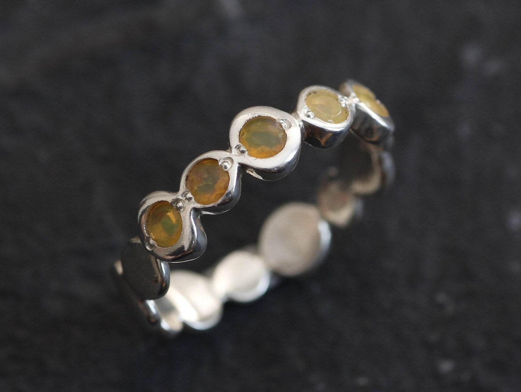 Yellow Ethiopian Fire Opal bezel tennis band eternity ring in sterling silver with diamond cut stones showing flashes of fire colors, a stylish jewelry design with bubble band details. Provides the benefit of a secure bezel setting and continuous gemstone glow, making it a meaningful October birthstone gift. Perfect for weddings, anniversaries, birthdays, and everyday wear.