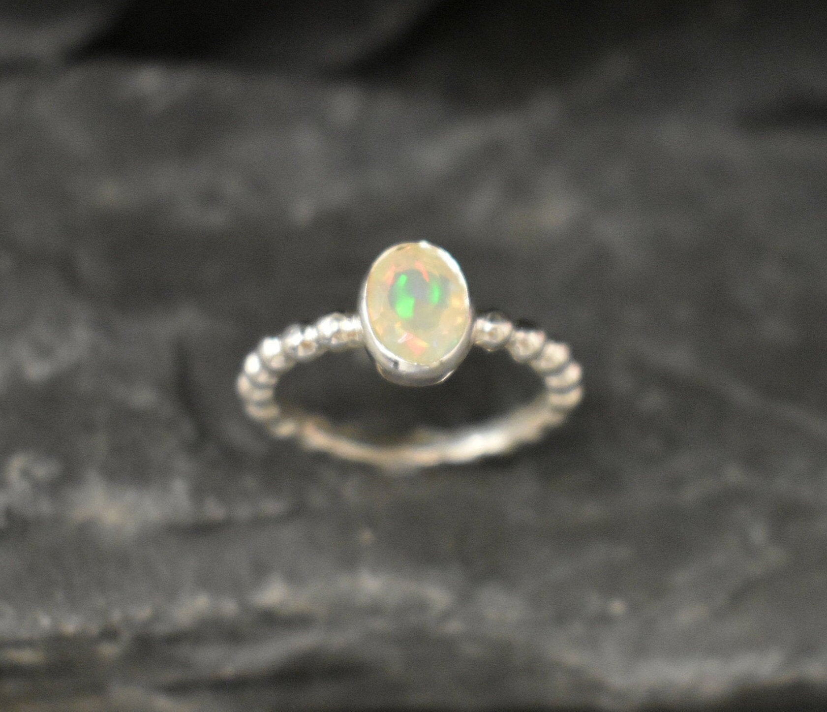 Fire Opal bezel bubble band ring in sterling silver with flashes of fire colors, a dainty jewelry style perfect for everyday elegance and stacking. Offers the benefit of durability with bezel setting and a glowing October birthstone gift idea for loved ones. Ideal to wear for birthdays, anniversaries, engagements, or casual celebrations.