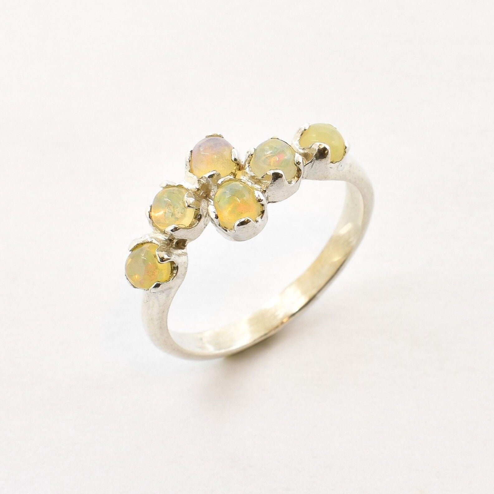 Fire Opal bypass ring in sterling silver with cabochon cut gemstones showcasing flashes of fire colors, crafted in a dainty jewelry style, believed to inspire joy and passion, a meaningful October birthstone gift idea for engagements, birthdays, and cocktail parties.