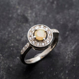 Ethiopian Opal diamond cut halo ring in solid 925 sterling silver, surrounded by sparkling CZ accents for brilliance and elegance. The halo design highlights flashes of fire colors while offering timeless durability. As the October Birthstone, Opal makes a meaningful gift for birthdays, engagements, anniversaries, or personal milestones. Perfect to wear at weddings, cocktail parties, and festive gatherings.
