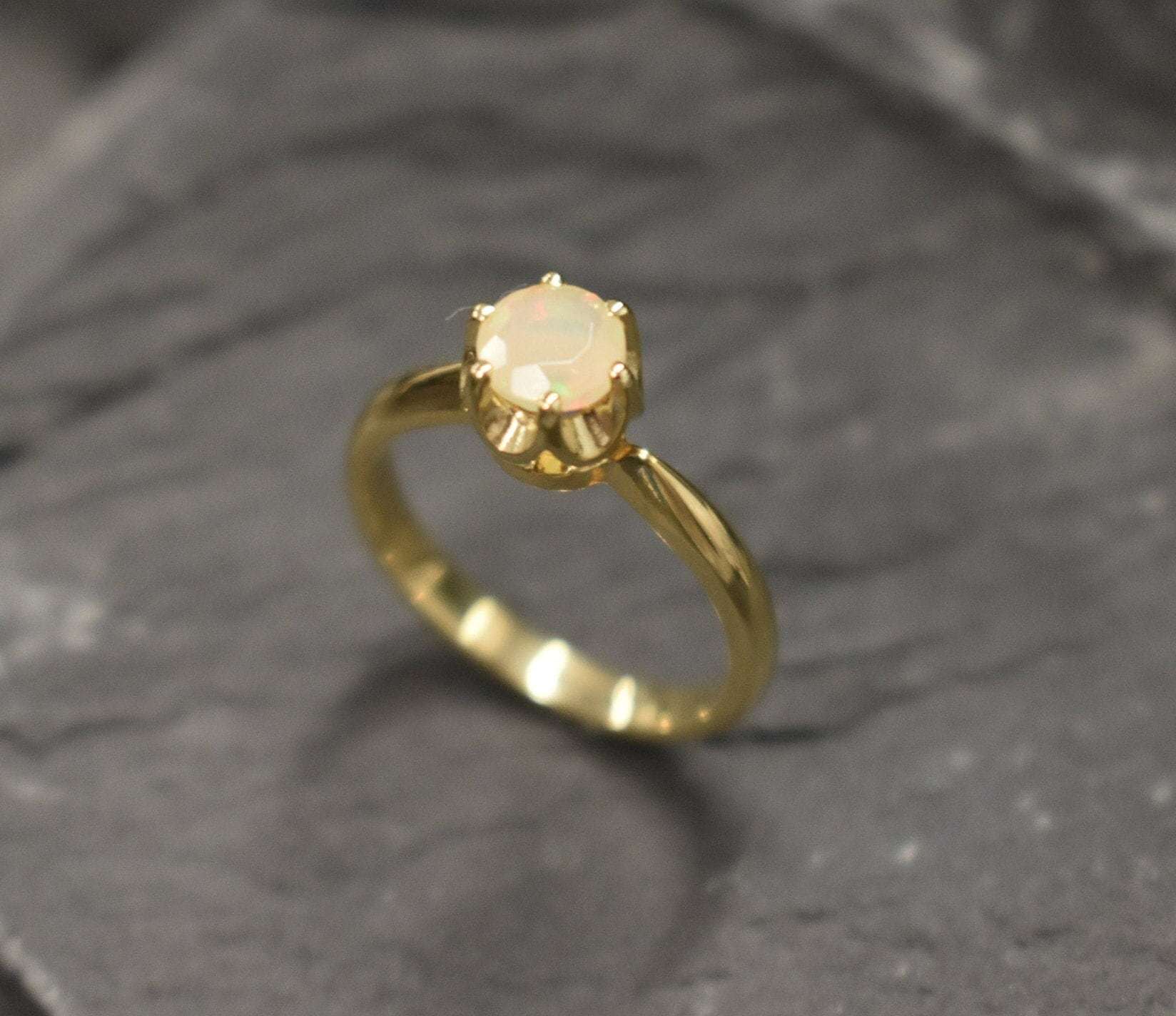 Natural Fire Opal Solitaire Ring in gold with a round cut stone held in a secure setting. The opal glows with flashes of fire colors, making it a timeless choice for a dainty promise ring or engagement ring. Fire Opal, the October birthstone, is believed to bring passion, inspiration, and joy. A meaningful gift for birthdays, anniversaries, and special milestones. Perfect for weddings, engagements, family gatherings, or everyday wear.