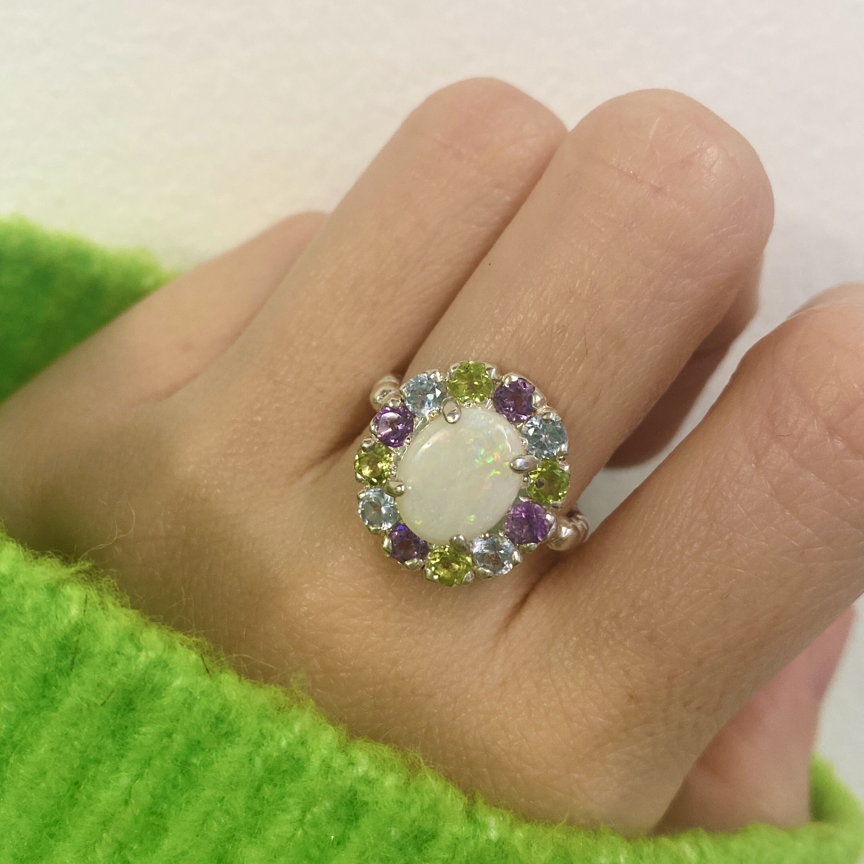 Flower Opal Ring styled for a cocktail look with nude nails and a cozy green sweater. The colorful cluster lifts mood and confidence. Ideal October birthstone gift for evening parties and holiday events.