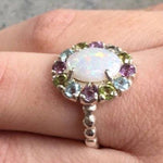 Flower Opal Ring with colorful Amethyst and Peridot accents, worn on ring finger with nude nails. Brings harmony and fresh energy. A thoughtful October gift for festivals, travel days and office parties.