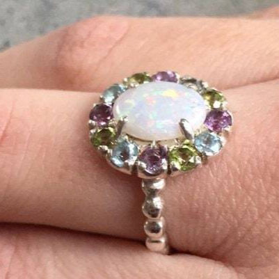 Flower Opal Ring with colorful Amethyst and Peridot accents, worn on ring finger with nude nails. Brings harmony and fresh energy. A thoughtful October gift for festivals, travel days and office parties.
