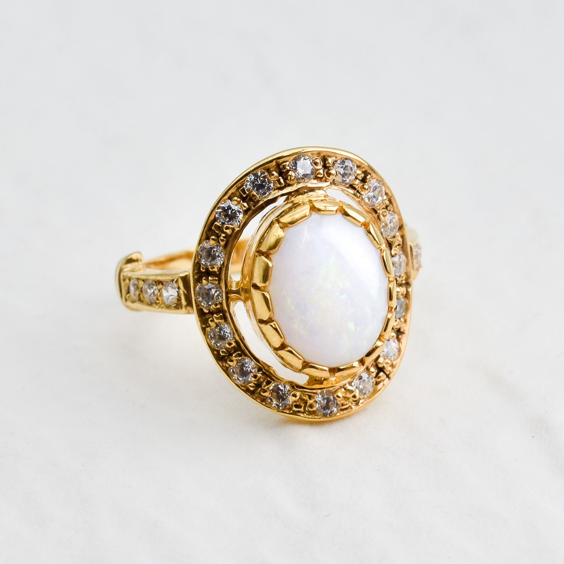 Natural Australian Opal statement ring in gold with halo of CZ diamonds, featuring an oval cabochon gemstone, ideal for glamorous statement style, believed to inspire creativity and love, a perfect October birthstone gift for anniversaries, engagements, and elegant celebrations.