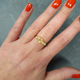Flower Opal Ring styled on middle  finger with bare nails, showcasing a bypass wrap with six Ethiopian opals, meaningful as an October birthstone gift, perfect for cocktail events and festive gatherings.