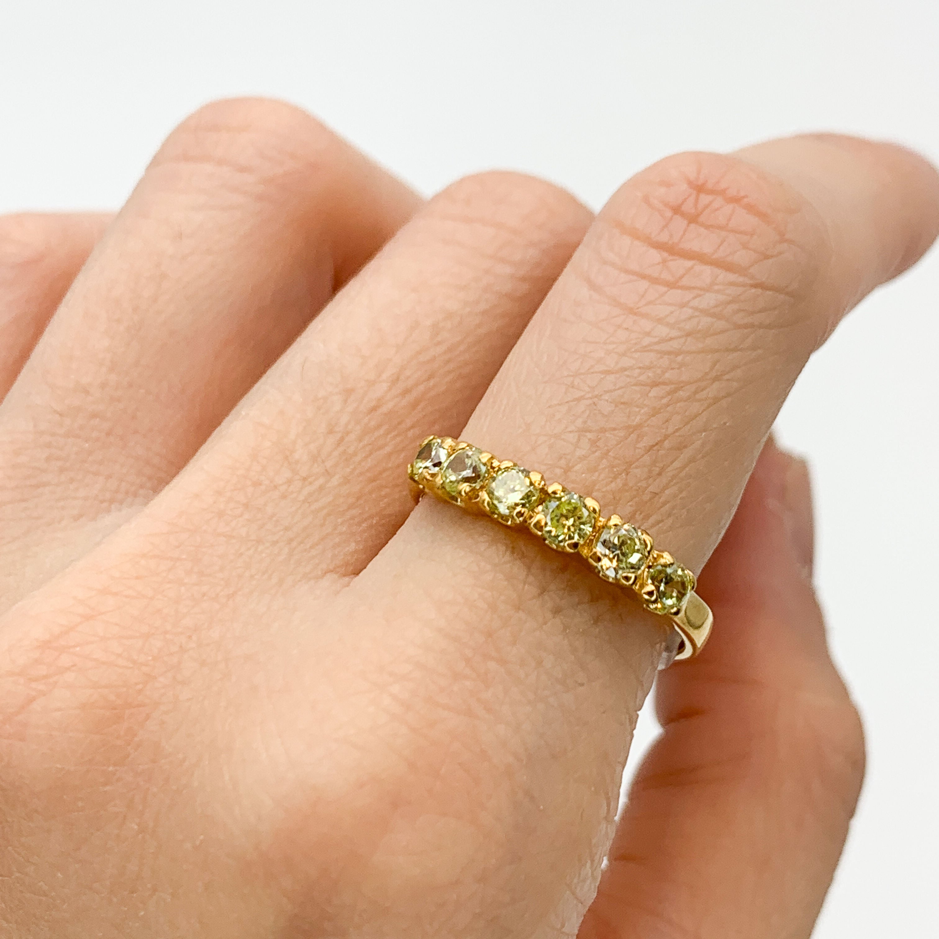 Gold peridot ring styled with natural skin tone and clean nails, perfect for both casual and elegant occasions, adding a touch of luxury and sparkle