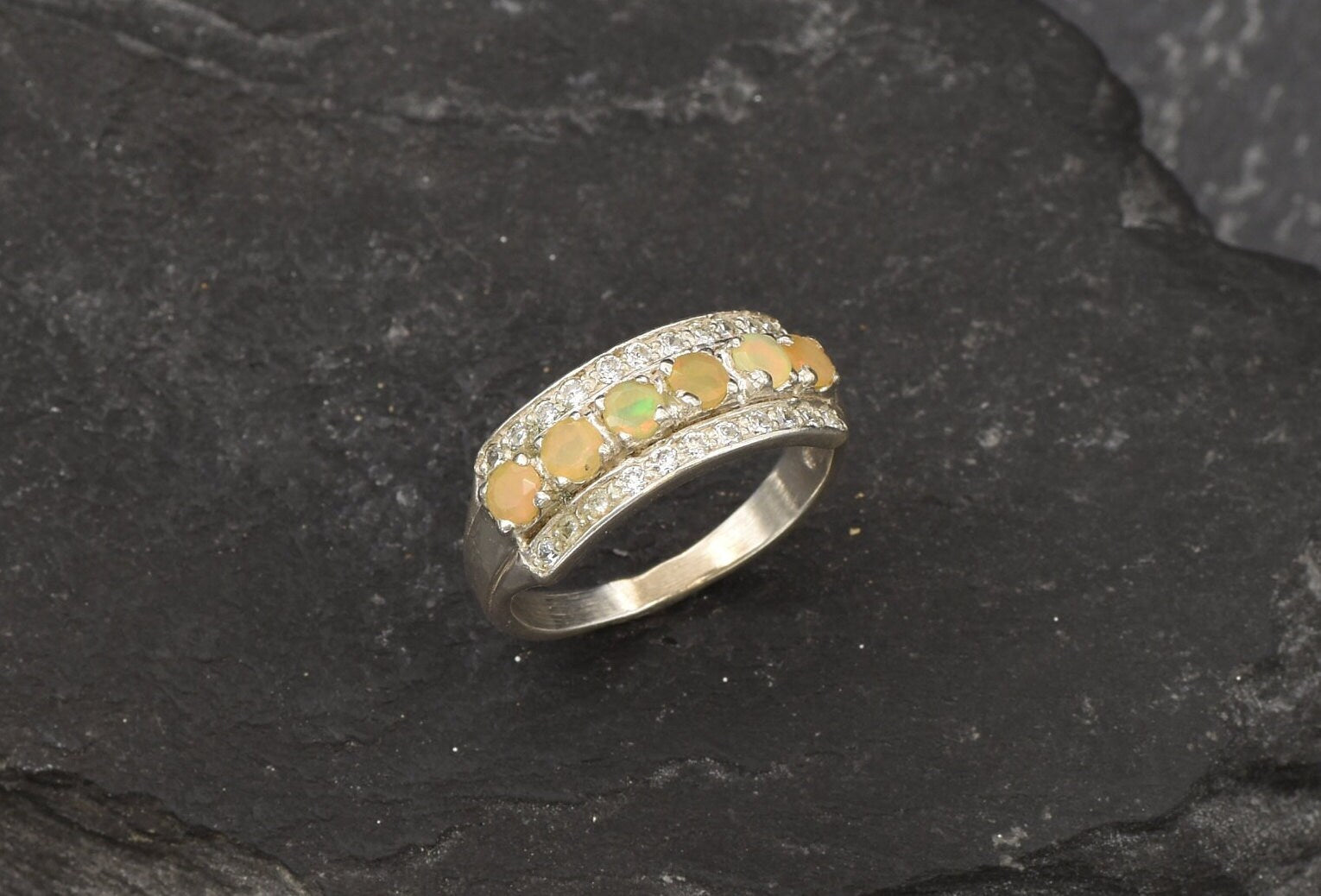 Opal Row Half Eternity Wide Ring in sterling silver featuring natural fire opals with flashes of fire colors, accented by CZ pave for a bold jewelry style. A meaningful October birthstone piece symbolizing balance and inspiration, making it a treasured gift idea. Perfect for weddings, anniversaries, cocktail events, and elegant evening occasions.