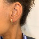 Woman wearing Hinged Hoop Earrings with Fishbone design, set in 18k Yellow Gold over solid 925 sterling silver, for casual wear.