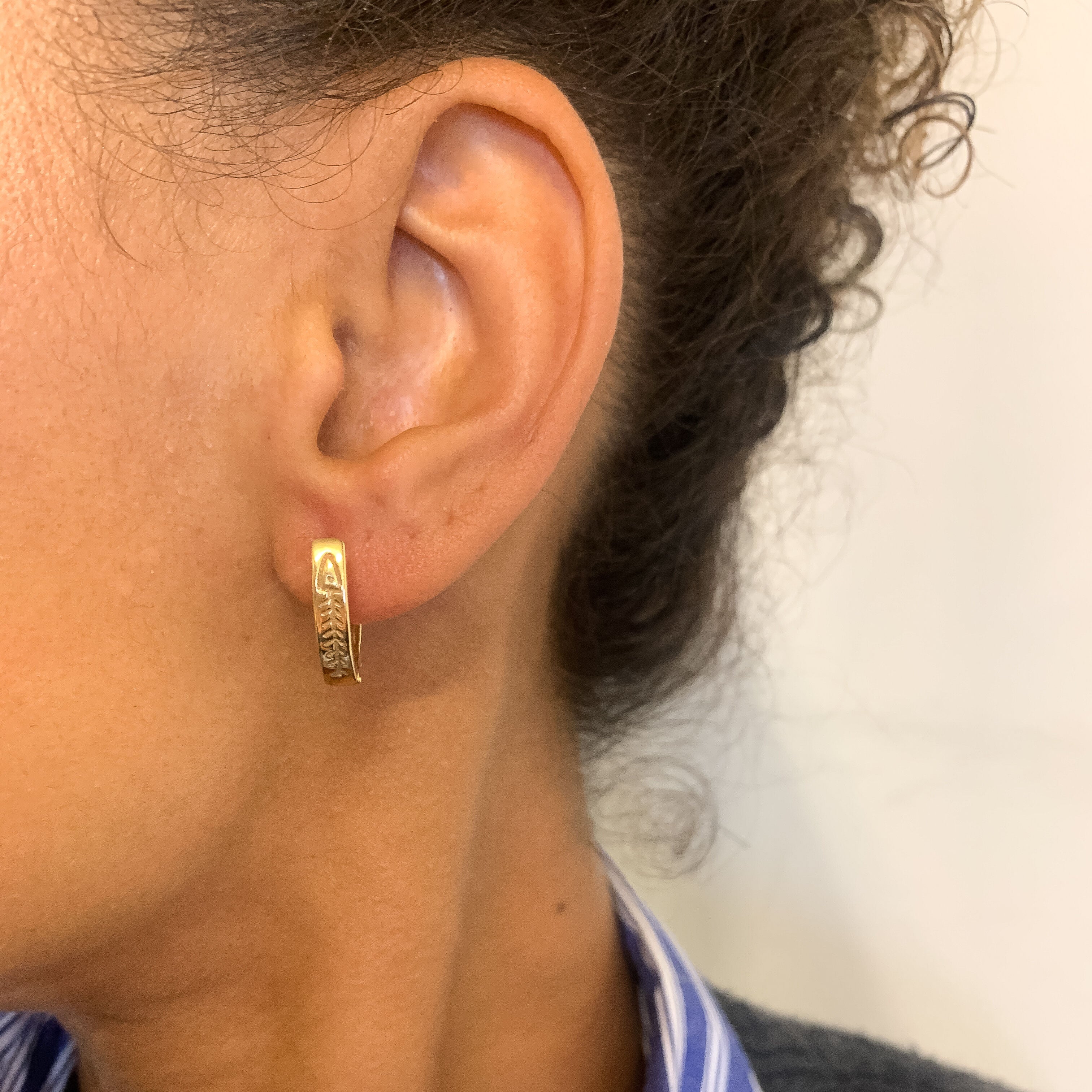 Woman wearing Hinged Hoop Earrings with Fishbone design, set in 18k Yellow Gold over solid 925 sterling silver, for casual wear.