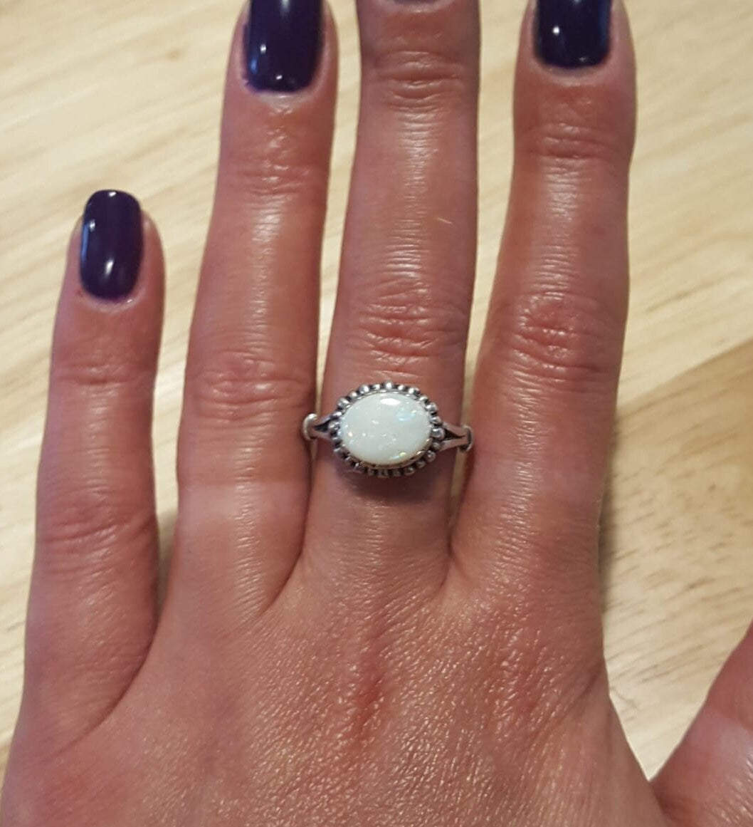 Horizontal Australian Opal Ring worn on middle finger with deep purple nails, white stone showing flashes of fire colors, stylish jewelry design that enhances confidence, symbolic October birthstone gift. Perfect for cocktail parties, evening dinners, and seasonal celebrations.