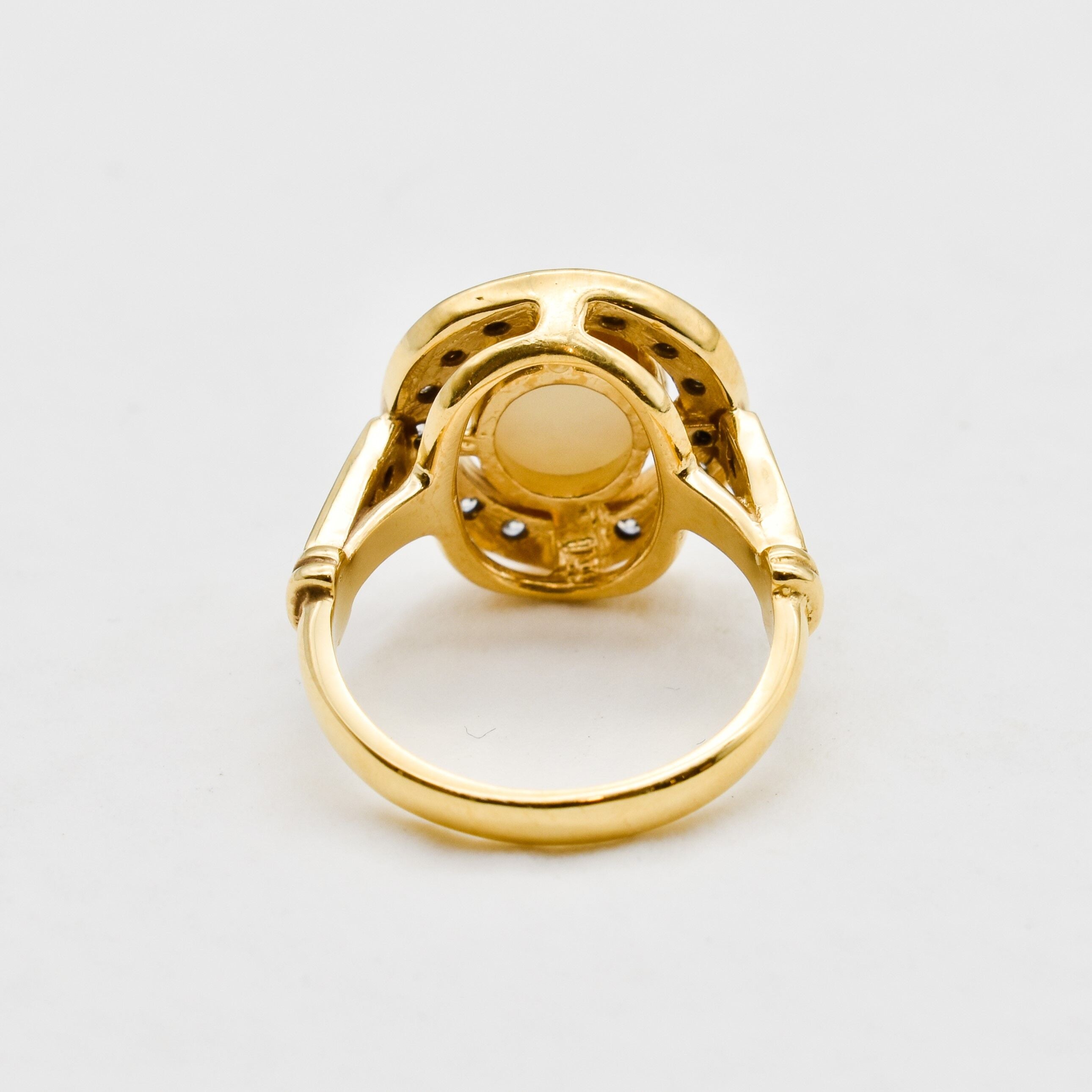 Australian Opal statement ring in gold with halo of CZ diamonds, featuring an oval cabochon gemstone, ideal for glamorous statement style, believed to inspire creativity and love, a perfect October birthstone gift for anniversaries, engagements, and elegant celebrations.