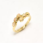 Fire Opal bypass ring in gold with cabochon cut gemstones showcasing flashes of fire colors, crafted in a dainty jewelry style, believed to inspire joy and passion, a meaningful October birthstone gift idea for engagements, birthdays, and cocktail parties.