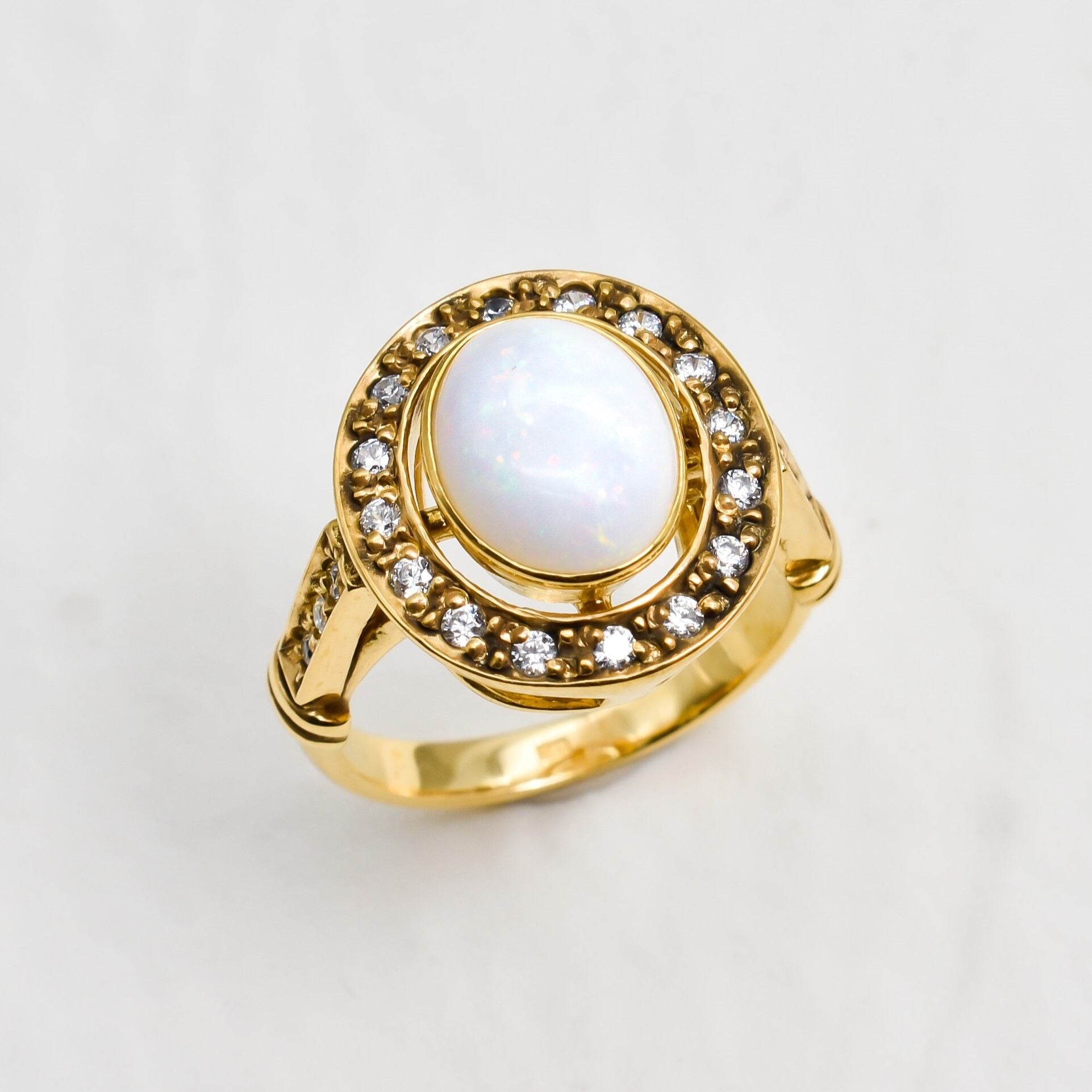 Natural Opal ring in gold with a halo of sparkling diamonds, featuring a cabochon cut gemstone for an elegant and timeless style. Known for promoting creativity and emotional balance, Opal is the October birthstone and makes a thoughtful gift for birthdays, anniversaries, weddings, or milestone celebrations.