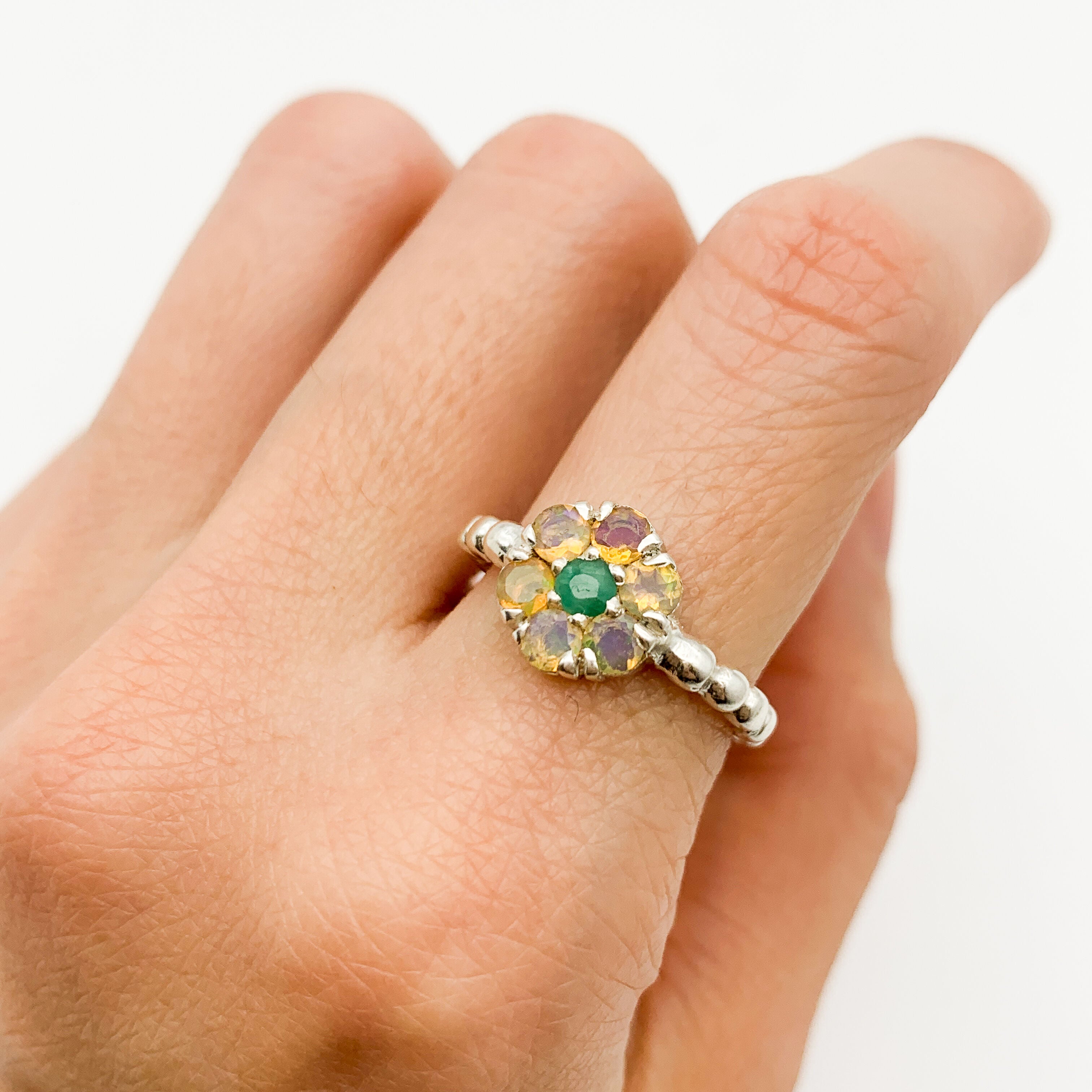 Flower Opal Ring worn on index finger with nude nails. Jewelry style is delicate and feminine with a floral gemstone design. Brings inspiration, creativity, growth and balance. Perfect October birthstone gift for birthdays or anniversaries. Suitable for weddings, dinner events and casual chic outfits.
