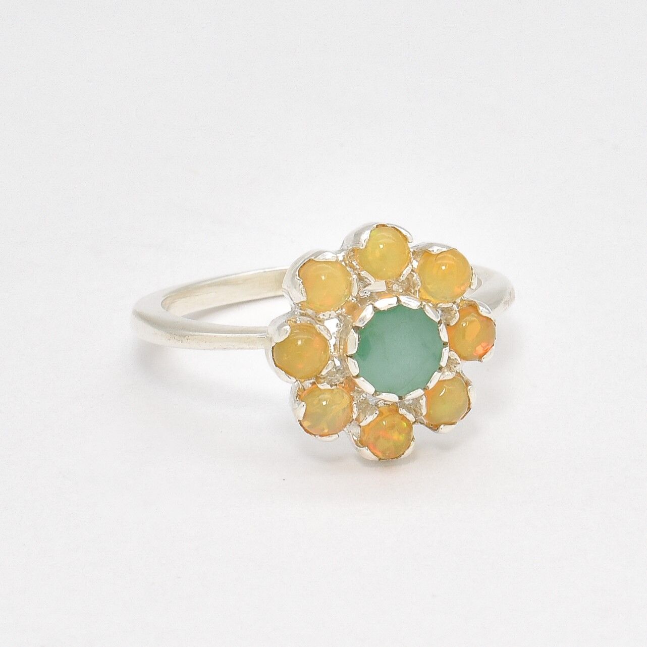 Natural Emerald and Opal Flower Ring in sterling silver with round cabochon opals surrounding a central emerald. Jewelry style is elegant, floral, and artistic with a timeless silver band. Emerald is linked to growth, renewal, and love while Opal is believed to inspire creativity and balance. A meaningful May or Birthstone birthstone gift for birthdays, anniversaries, or special celebrations. Ideal for weddings, garden parties, formal gatherings, or daily elegance.