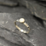 Opal Ring in sterling silver with a hammered textured band and bezel set white opal that shows flashes of fire colors. Opal is linked to creativity, inspiration and emotional balance, making it a meaningful October birthstone gift. A perfect present for birthdays, anniversaries or promise rings. Suitable for daily wear, weddings, parties and special occasions.