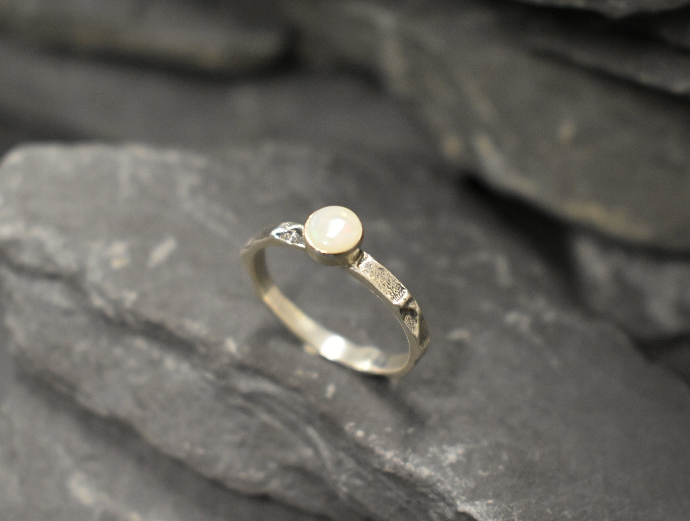 Opal Ring in sterling silver with a hammered textured band and bezel set white opal that shows flashes of fire colors. Opal is linked to creativity, inspiration and emotional balance, making it a meaningful October birthstone gift. A perfect present for birthdays, anniversaries or promise rings. Suitable for daily wear, weddings, parties and special occasions.