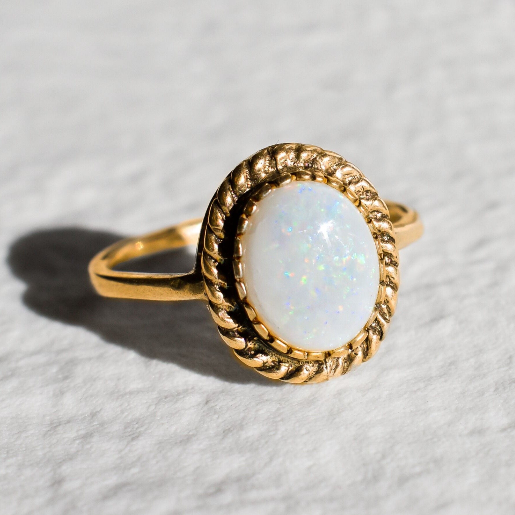Natural Australian Opal gold ring with an oval cabochon cut gemstone framed by an intricate rope-edge design, offering a classic and elegant style. Opal, the October birthstone, is known for inspiring creativity and emotional harmony, making it an ideal gift for birthdays, anniversaries, weddings, or special celebrations.