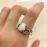 White Opal Vine Ring worn on the index finger with bare nails, vine and leaf details embracing the cabochon stone with flashes of fire colors. A nature-inspired October Birthstone jewelry piece perfect for casual day outings and weekend picnics.