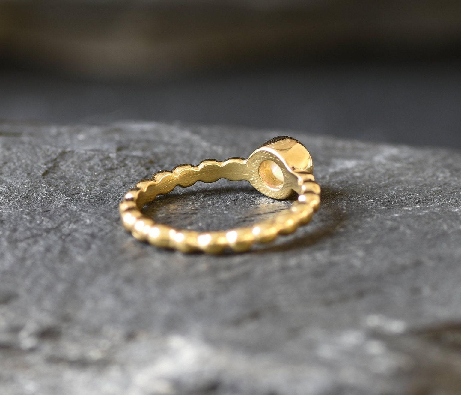 Ethiopian Opal Bezel Promise Ring in gold featuring a round diamond cut stone set in a bubble tennis band design, a stylish jewelry piece radiating flashes of fire colors while symbolizing love and commitment, making it a meaningful October birthstone gift idea. Perfect for engagements, anniversaries, and elegant evening occasions to showcase understated brilliance.