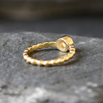 Ethiopian Opal Bezel Promise Ring in gold featuring a round diamond cut stone set in a bubble tennis band design, a stylish jewelry piece radiating flashes of fire colors while symbolizing love and commitment, making it a meaningful October birthstone gift idea. Perfect for engagements, anniversaries, and elegant evening occasions to showcase understated brilliance.