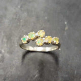 Ethiopian Opal Bypass Ring in silver with six cabochon stones aligned in a curved wrap setting, a stylish jewelry design that radiates flashes of fire colors and adds a modern edge, making it a thoughtful October birthstone gift idea. Perfect to wear at weddings, cocktail parties, and romantic dinners for a bold yet refined look.