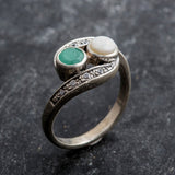 Opal and Emerald Two-Stone Bypass Wave Ring featuring white Opal with flashes of fire colors paired with real green Emerald, accented by CZ pave stones for timeless jewelry style. This design balances elegance with symbolism, making it an ideal October and May birthstone gift idea. Perfect for weddings, anniversaries, cocktail parties, and celebratory events where sophistication is desired.