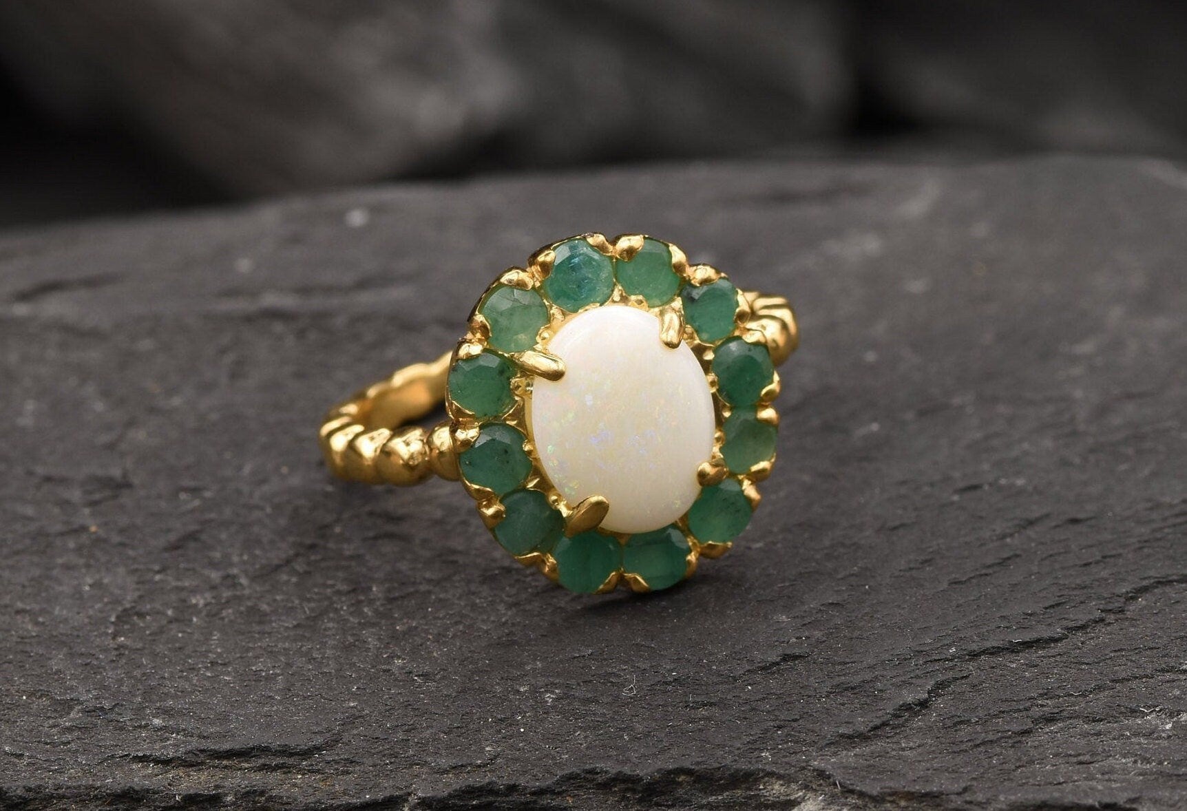 Opal halo floral ring with Genuine Emeralds in a vintage victorian flower halo, White cabochon center, and beaded Bubble Band for a bold statement cocktail look showing flashes of fire colors. Benefits include creativity, harmony, and calm. Ideal October birthstone gift with meaningful May emerald accents.
Worn for weddings, cocktail parties, anniversaries, graduations, garden events, and holiday gatherings.