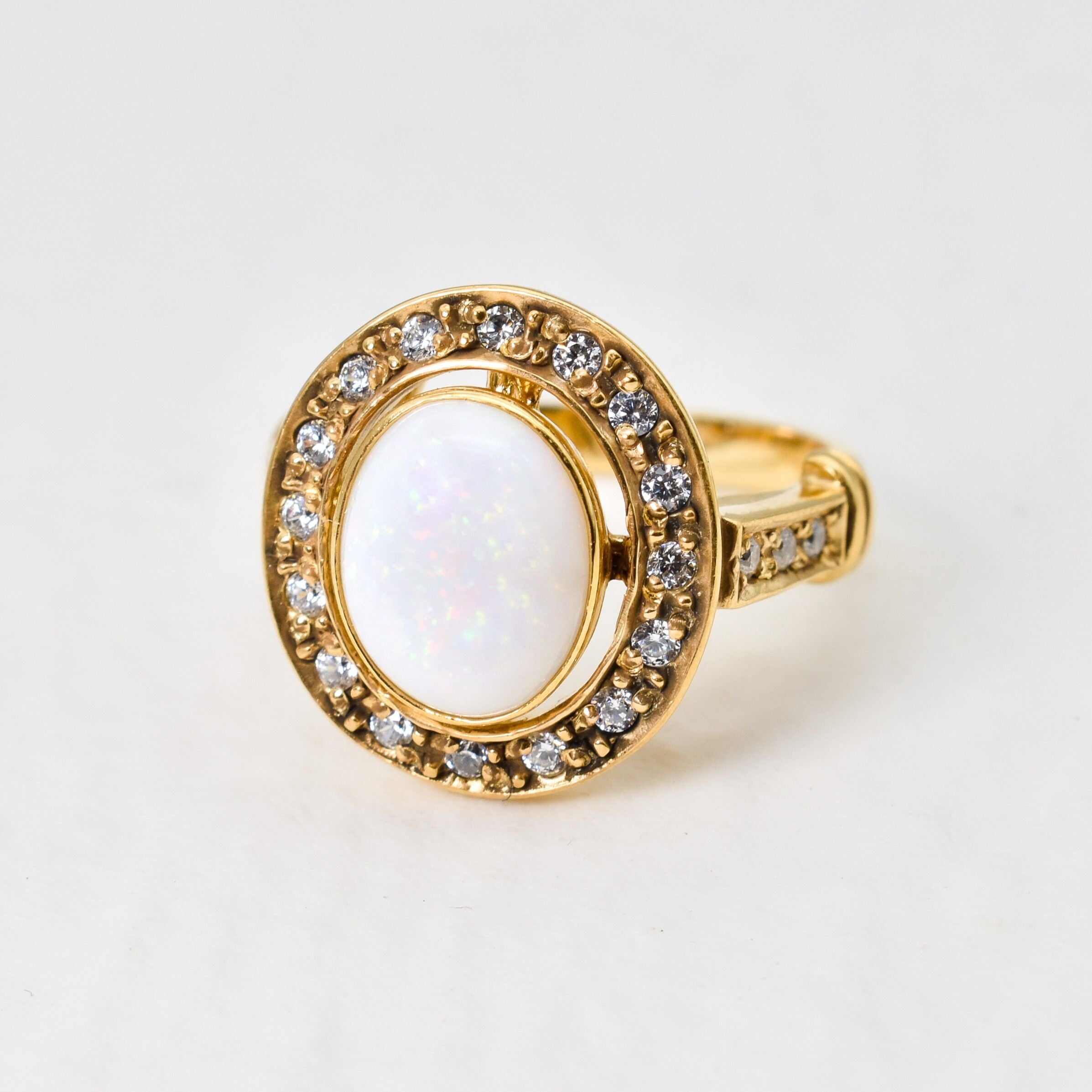 Natural Opal ring in gold with a halo of sparkling diamonds, featuring a cabochon cut gemstone for an elegant and timeless style. Known for promoting creativity and emotional balance, Opal is the October birthstone and makes a thoughtful gift for birthdays, anniversaries, weddings, or milestone celebrations.