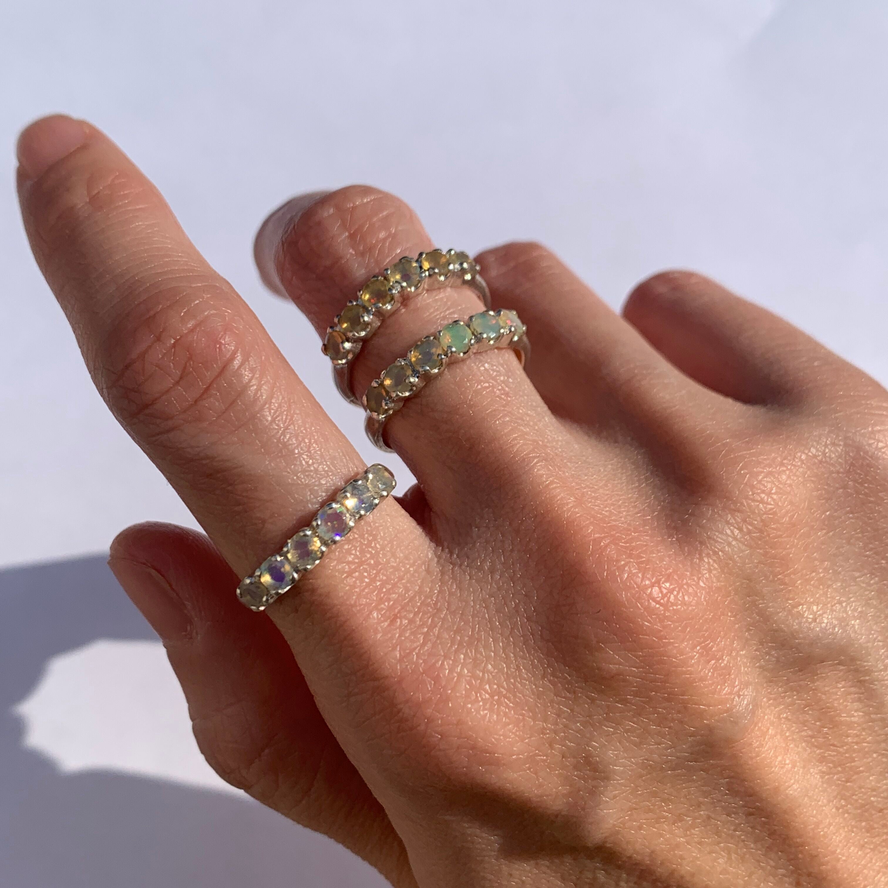 Opal Half Eternity Ring worn on index finger with natural nails, a dainty silver band perfect for everyday elegance and October birthstone energy, suited for casual outings or office wear.