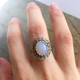 Natural Australian Opal cabochon halo sterling silver ring worn with a soft neutral background, ideal for complementing elegant dresses or evening wear, and perfect for milestone celebrations, anniversaries, and engagement occasions.