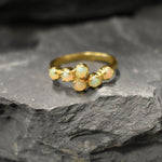 Ethiopian Opal Bypass Ring in gold with six cabochon stones aligned in a curved wrap setting, a stylish jewelry design that radiates flashes of fire colors and adds a modern edge, making it a thoughtful October birthstone gift idea. Perfect to wear at weddings, cocktail parties, and romantic dinners for a bold yet refined look.