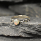 Opal Ring in sterling silver with a hammered textured band and bezel set white opal that shows flashes of fire colors. Opal is linked to creativity, inspiration and emotional balance, making it a meaningful October birthstone gift. A perfect present for birthdays, anniversaries or promise rings. Suitable for daily wear, weddings, parties and special occasions.