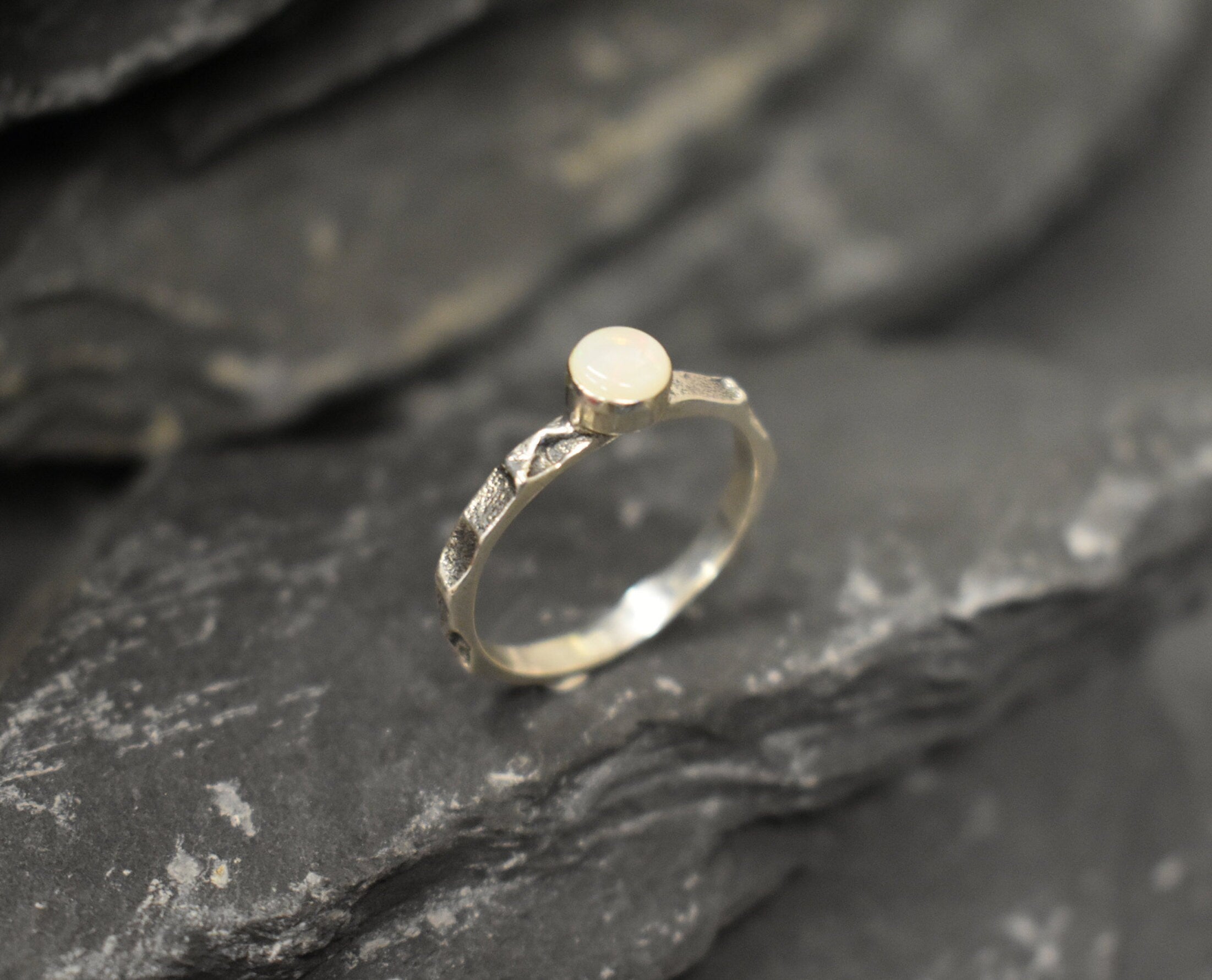 Opal Ring in sterling silver with a hammered textured band and bezel set white opal that shows flashes of fire colors. Opal is linked to creativity, inspiration and emotional balance, making it a meaningful October birthstone gift. A perfect present for birthdays, anniversaries or promise rings. Suitable for daily wear, weddings, parties and special occasions.