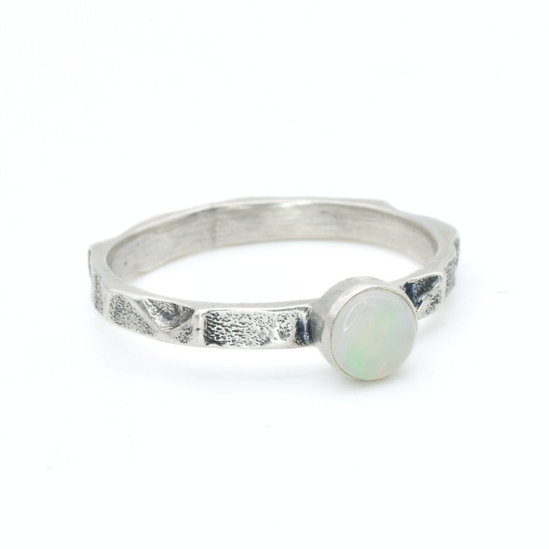 Opal Ring in sterling silver with a hammered textured band and bezel set white opal that shows flashes of fire colors. Opal is linked to creativity, inspiration and emotional balance, making it a meaningful October birthstone gift. A perfect present for birthdays, anniversaries or promise rings. Suitable for daily wear, weddings, parties and special occasions.