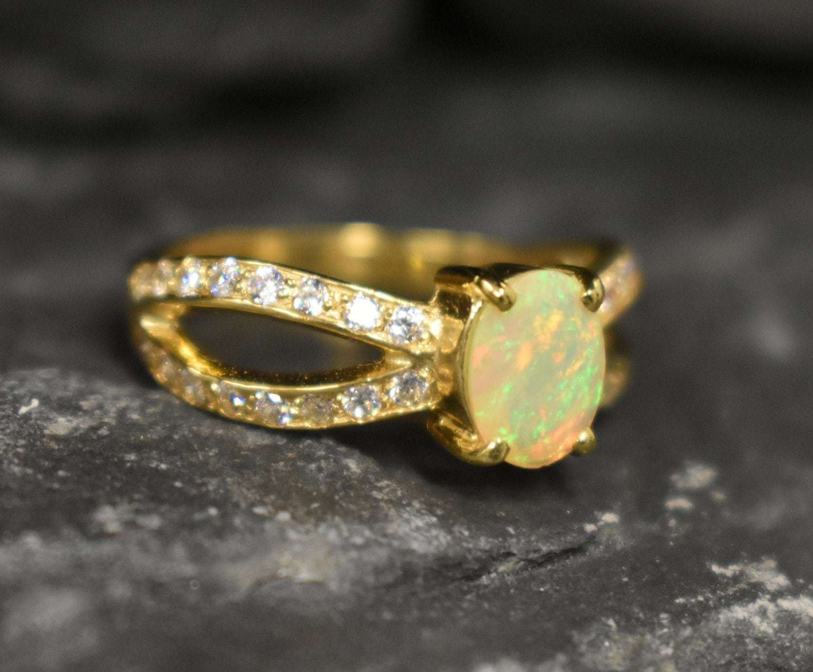 Opal Ring with split shank band and CZ pave setting showing flashes of fire colors, designed as elegant fine jewelry. Known for its emotional healing and creativity benefits, Opal is also the October birthstone and a thoughtful gift for birthdays or anniversaries. Perfect to wear at weddings, romantic dinners, and special evening celebrations.