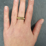 Opal Rope Row Ring styled on middle finger with bare nails, its cabochon opals shimmering with fire colors. A versatile October birthstone piece that enhances elegance, suitable for gifting loved ones, and perfect for casual brunches, birthdays, and celebratory occasions.