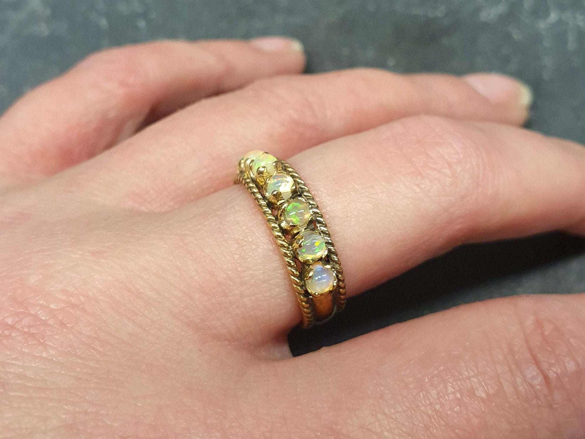 Opal Rope Row Ring worn on middle finger with nude nails, styled to highlight its cabochon opals and flashes of fire colors. A chic accessory that adds balance and clarity, ideal October birthstone jewelry gift, perfect for weddings, evening dinners, and sophisticated outings.