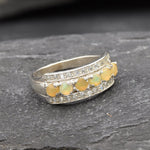Opal Row Half Eternity Wide Ring in sterling silver featuring natural fire opals with flashes of fire colors, accented by CZ pave for a bold jewelry style. A meaningful October birthstone piece symbolizing balance and inspiration, making it a treasured gift idea. Perfect for weddings, anniversaries, cocktail events, and elegant evening occasions.